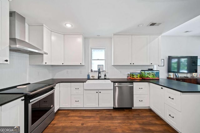 kitchen featuring wall chimney exhaust hood, dark hardwood / wood-style floors, stainless steel appliances, white cabinetry, and sink