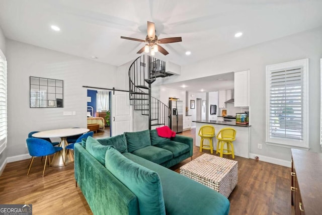 living room with light wood-type flooring, ceiling fan, and a barn door