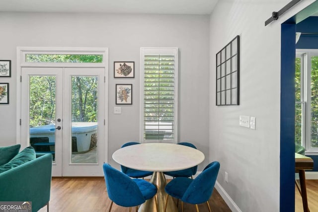 dining space featuring french doors, a barn door, and light hardwood / wood-style flooring