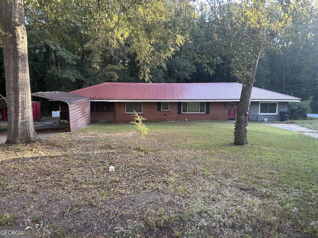 single story home with a front yard, brick siding, and metal roof