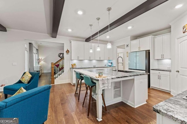 kitchen with beamed ceiling, wood-type flooring, sink, light stone countertops, and decorative light fixtures