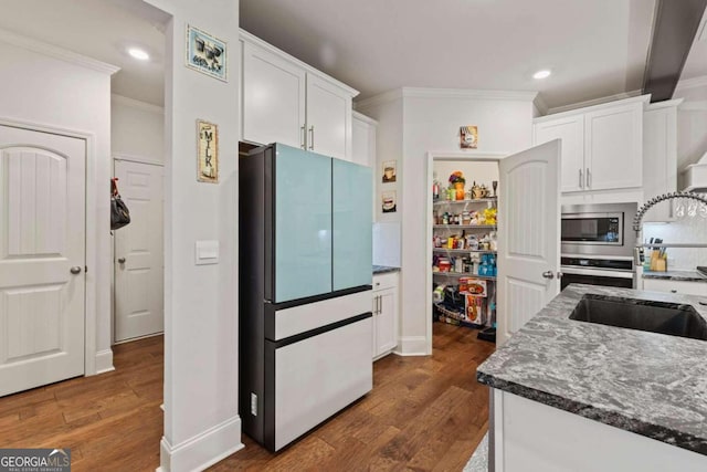 kitchen with ornamental molding, fridge, white cabinetry, and dark wood-type flooring