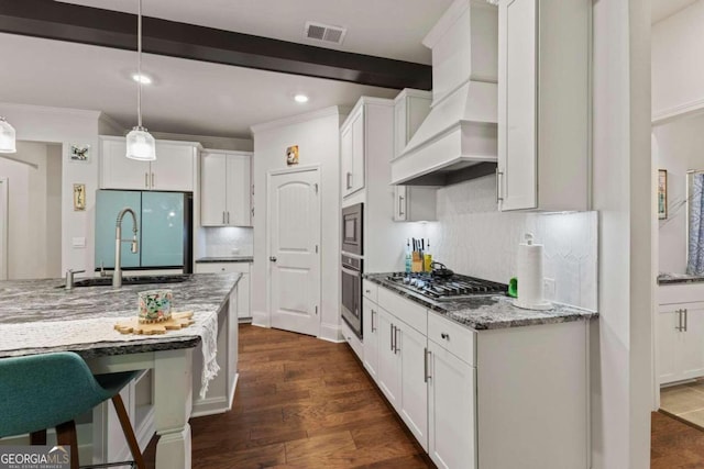 kitchen with dark wood-type flooring, hanging light fixtures, stainless steel appliances, white cabinetry, and light stone counters