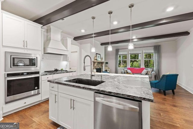 kitchen featuring sink, stainless steel appliances, custom exhaust hood, white cabinets, and beam ceiling