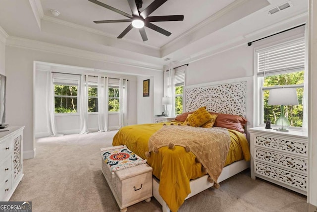 carpeted bedroom featuring ornamental molding, a tray ceiling, and ceiling fan