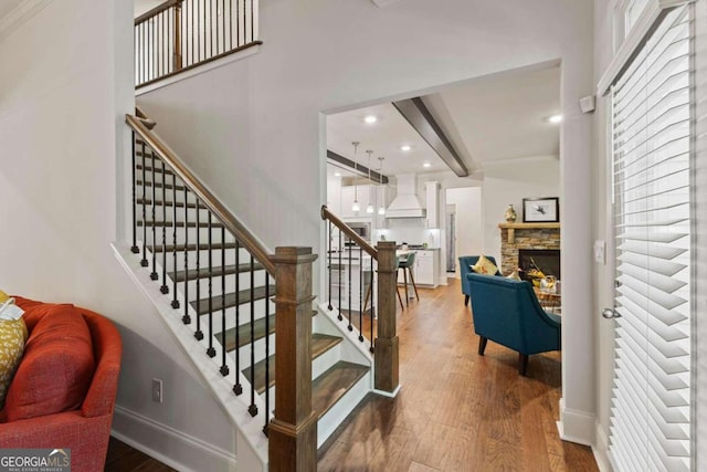 staircase featuring wood-type flooring and a fireplace