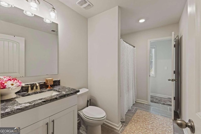 bathroom featuring toilet, walk in shower, vanity, and tile patterned flooring