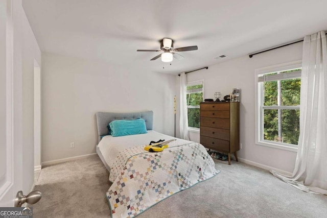 bedroom featuring ceiling fan, light carpet, and multiple windows