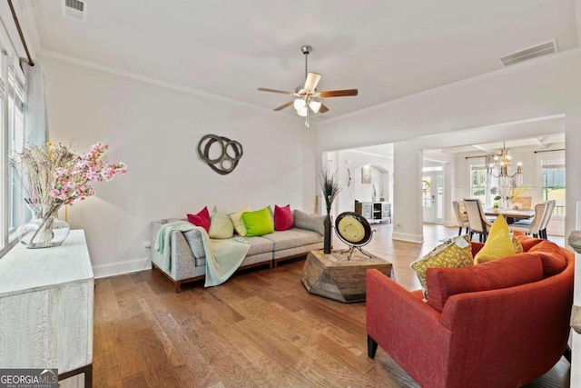 living room featuring crown molding, wood-type flooring, and ceiling fan with notable chandelier