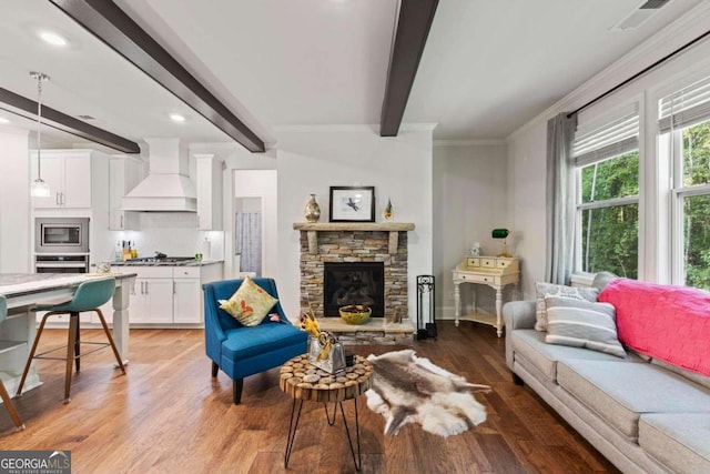 living room featuring beam ceiling, wood-type flooring, ornamental molding, and a fireplace