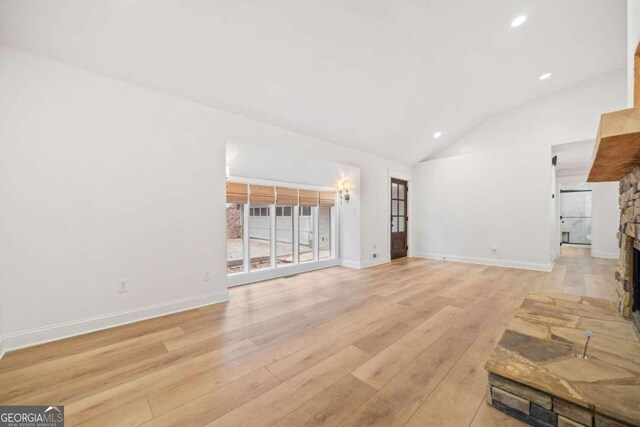 unfurnished living room featuring a fireplace, light hardwood / wood-style floors, and lofted ceiling