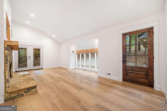 unfurnished living room featuring lofted ceiling, french doors, and light hardwood / wood-style flooring