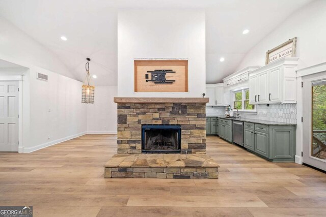 living room featuring a stone fireplace, sink, high vaulted ceiling, and light hardwood / wood-style floors