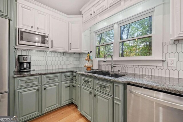 kitchen featuring white cabinets, appliances with stainless steel finishes, dark stone counters, and sink