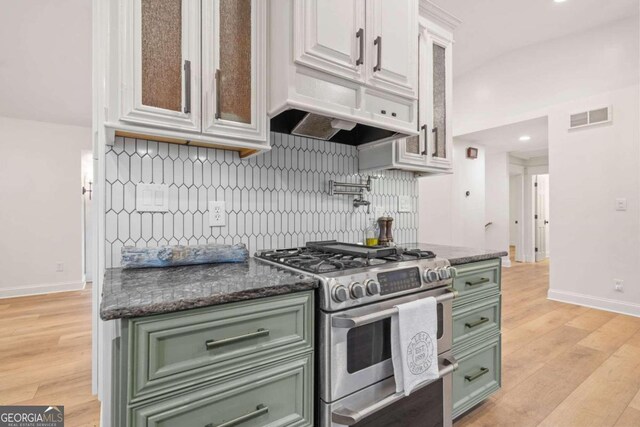 kitchen with white cabinets, light hardwood / wood-style floors, double oven range, and tasteful backsplash