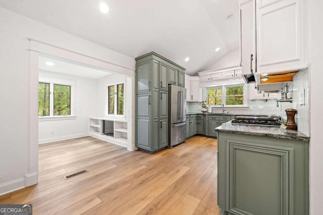 kitchen with high end refrigerator, a healthy amount of sunlight, lofted ceiling, and light wood-type flooring