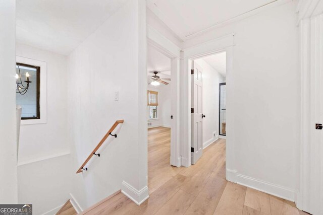 hallway with light hardwood / wood-style flooring and a notable chandelier