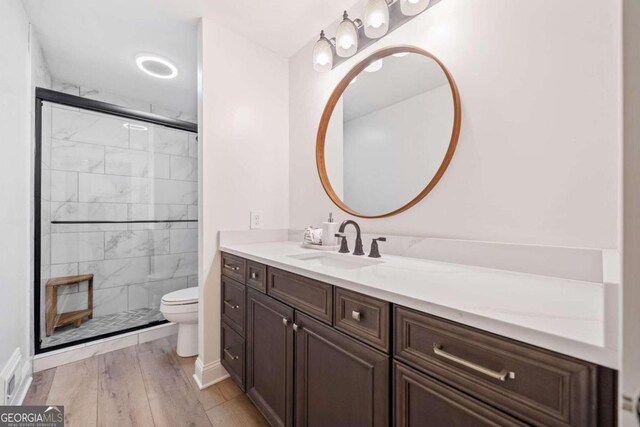 bathroom with hardwood / wood-style flooring, vanity, toilet, and a shower with door