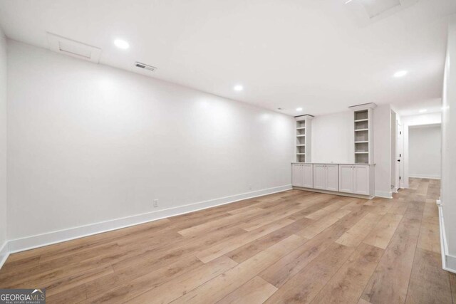 unfurnished room featuring built in features and light hardwood / wood-style floors