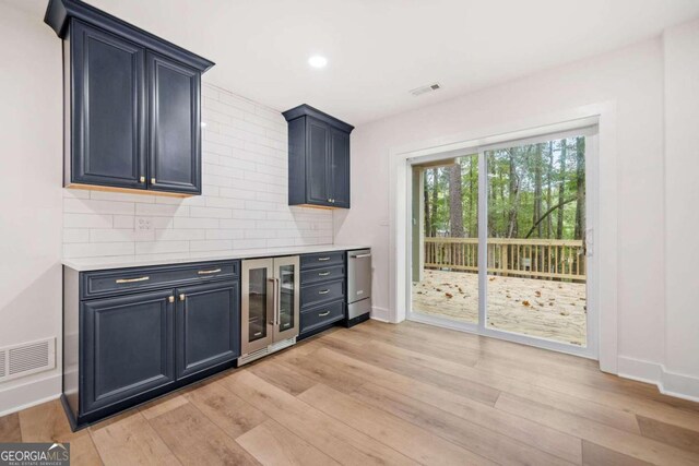 bar with light wood-type flooring, tasteful backsplash, stainless steel dishwasher, and beverage cooler