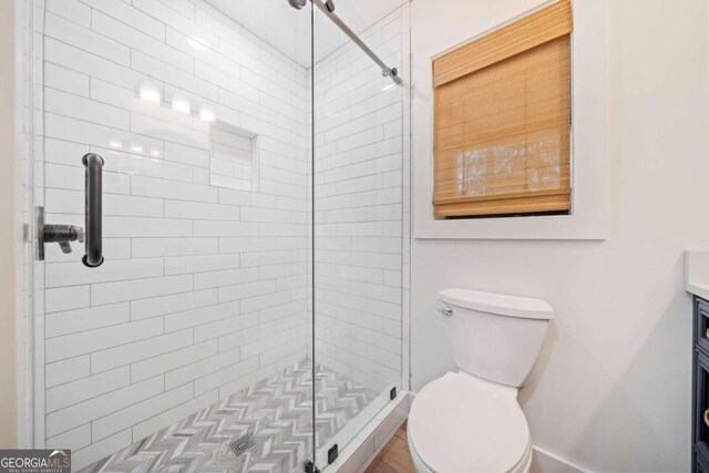 bathroom with tiled shower, vanity, and toilet