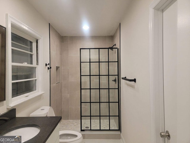 bathroom featuring vanity, toilet, and tiled shower