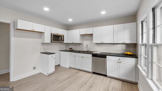 kitchen with appliances with stainless steel finishes, tasteful backsplash, sink, light hardwood / wood-style flooring, and white cabinets