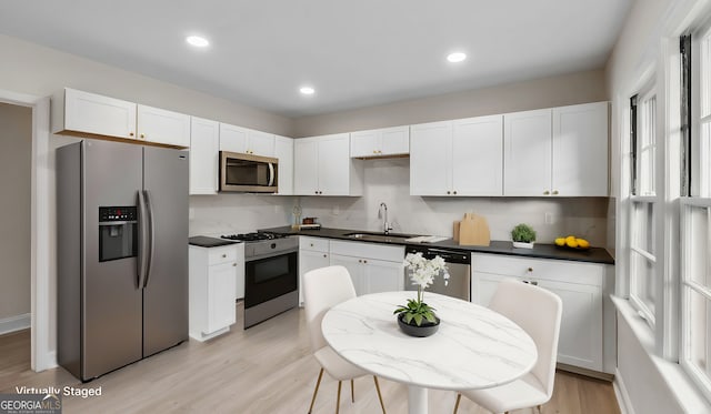 kitchen with white cabinetry, sink, appliances with stainless steel finishes, and light hardwood / wood-style flooring