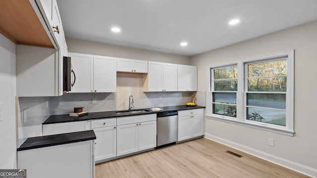 kitchen featuring white cabinetry, sink, tasteful backsplash, stainless steel dishwasher, and light hardwood / wood-style floors