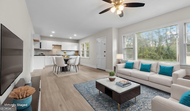 living room featuring ceiling fan, light hardwood / wood-style flooring, and sink