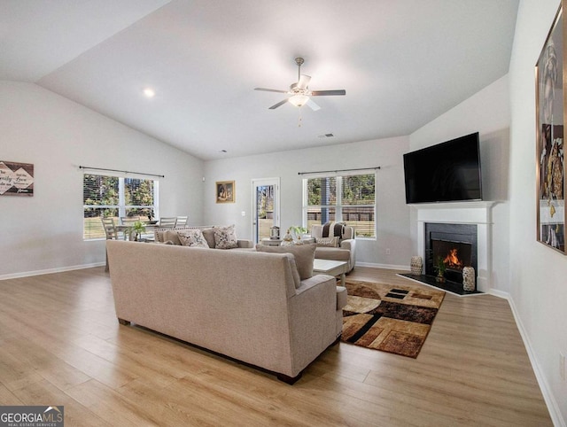 living room with a wealth of natural light, light hardwood / wood-style flooring, ceiling fan, and lofted ceiling