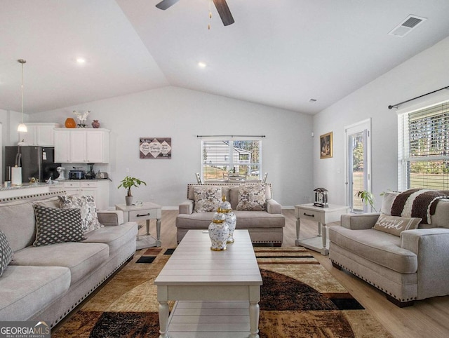 living room featuring light hardwood / wood-style flooring, vaulted ceiling, and ceiling fan