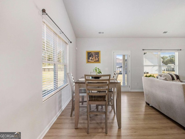 dining space featuring hardwood / wood-style floors and vaulted ceiling