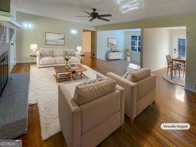 living room featuring ceiling fan, a textured ceiling, and hardwood / wood-style floors