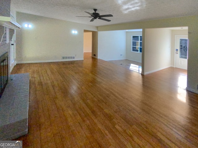 unfurnished living room featuring ceiling fan, hardwood / wood-style flooring, and a textured ceiling