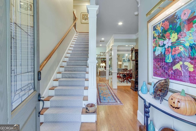 entrance foyer with light hardwood / wood-style floors, crown molding, and decorative columns