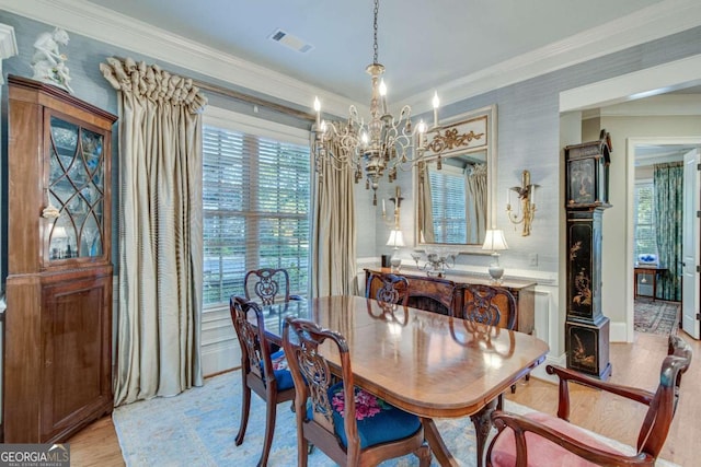 dining area with an inviting chandelier, ornamental molding, and light hardwood / wood-style floors