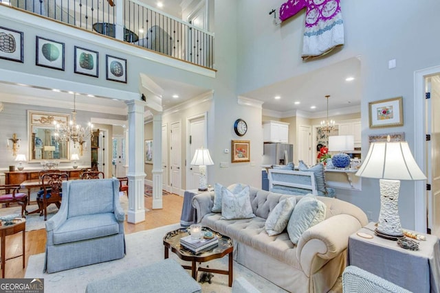 living room with ornamental molding, decorative columns, light hardwood / wood-style flooring, and a towering ceiling