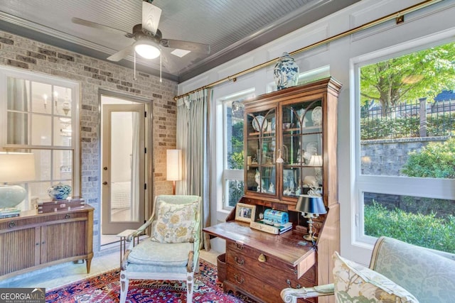 sitting room with ornamental molding, brick wall, and ceiling fan