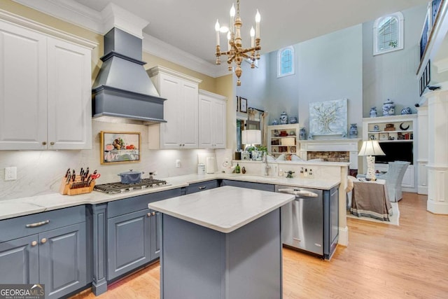 kitchen with a center island, white cabinetry, stainless steel appliances, pendant lighting, and custom exhaust hood