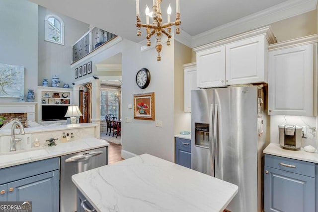 kitchen with white cabinets, sink, pendant lighting, crown molding, and stainless steel appliances