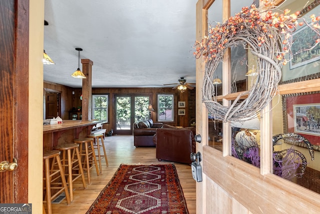 interior space with ceiling fan, bar, wood-type flooring, and wooden walls