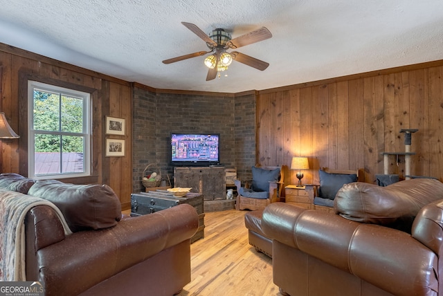 living room featuring ceiling fan, wood walls, and light hardwood / wood-style flooring