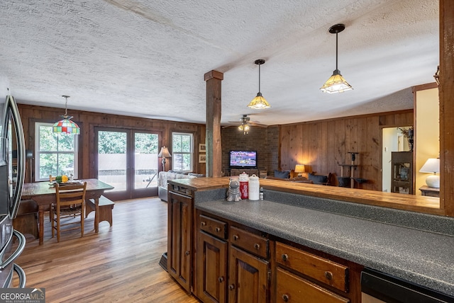 kitchen with a textured ceiling, ceiling fan, wood-type flooring, and wood walls