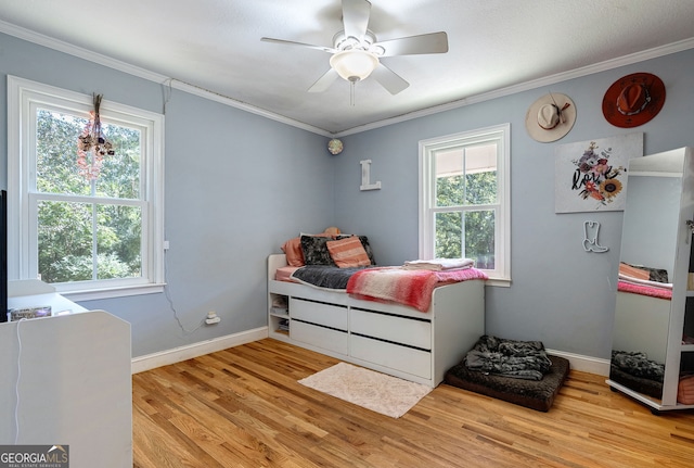 bedroom with ceiling fan, crown molding, multiple windows, and light wood-type flooring