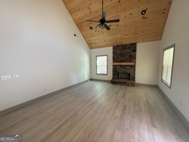 unfurnished living room with light wood-type flooring, a stone fireplace, ceiling fan, wooden ceiling, and high vaulted ceiling