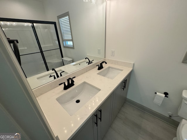 bathroom with toilet, an enclosed shower, and vanity