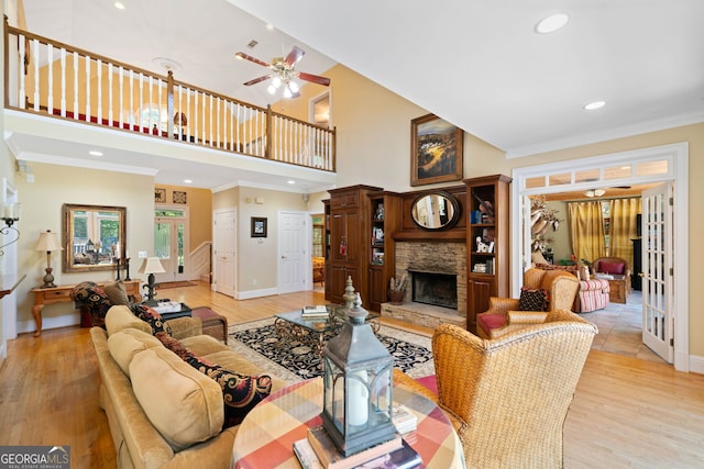 living room with crown molding, a fireplace, light wood-type flooring, and ceiling fan