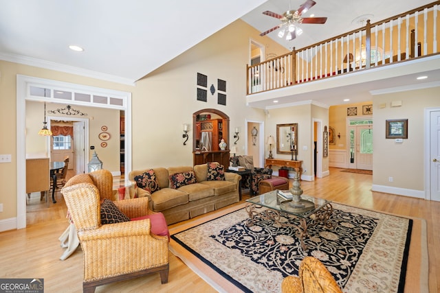 living room featuring ornamental molding, a high ceiling, and light wood-type flooring