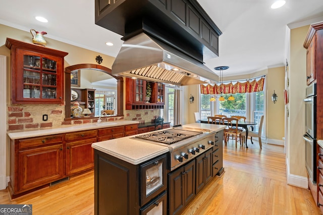 kitchen featuring stainless steel gas stovetop, tasteful backsplash, a center island, and light wood-type flooring